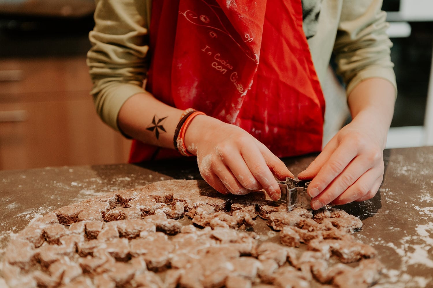 young girl with a red apron baking german cinnamon stars for Christmas