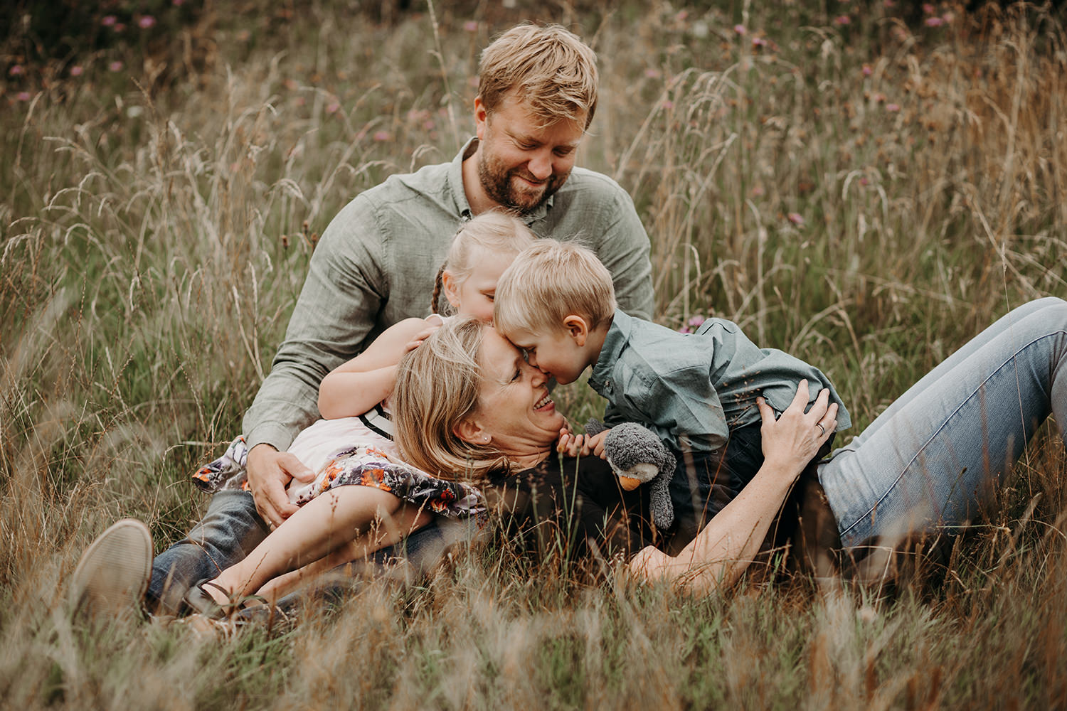 Gezinsfotoshoot buiten in het veld met kinderen.