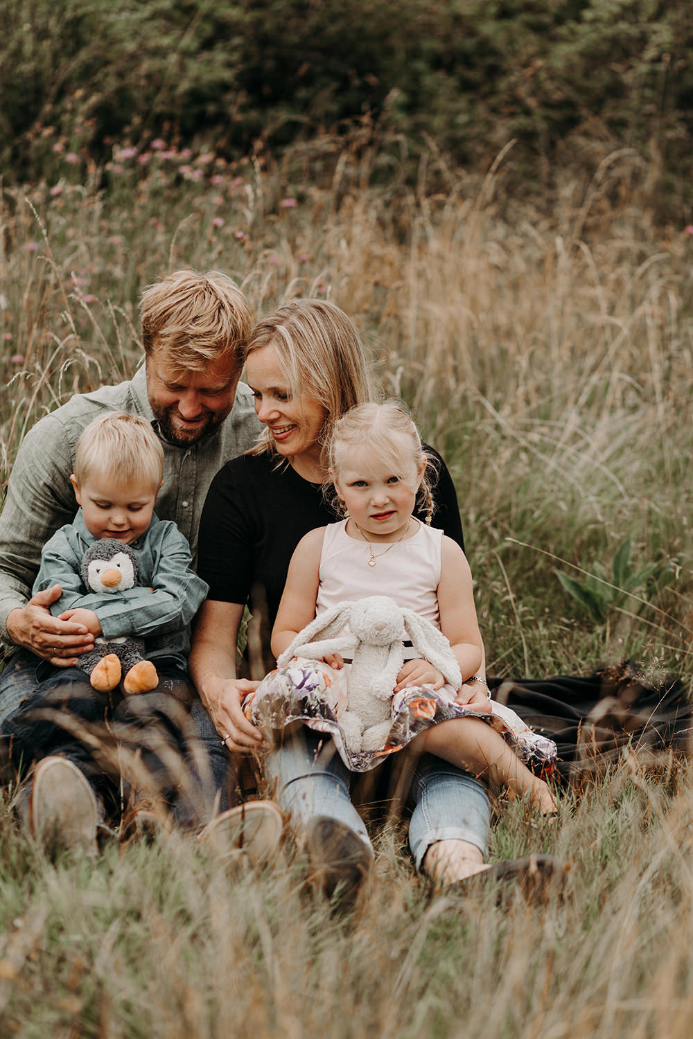 Een gezin poseert buiten in het hoge gras voor een gezinsfotoshoot buiten.