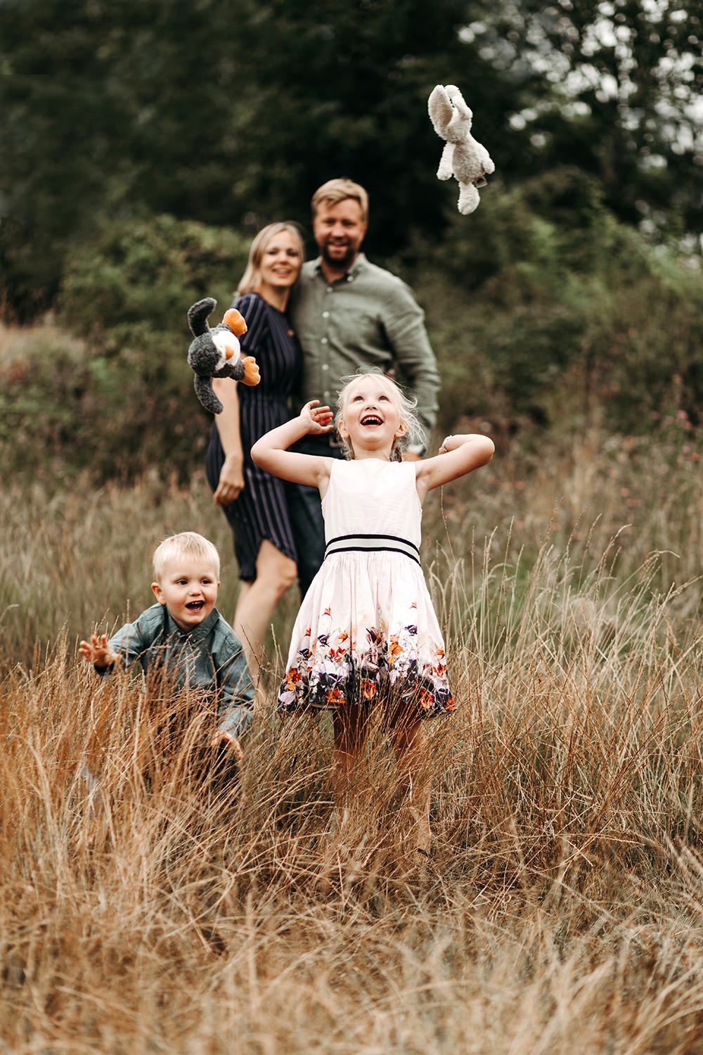 Gezinsfotoshoot buiten met gezin van vier en een knuffelbeer.