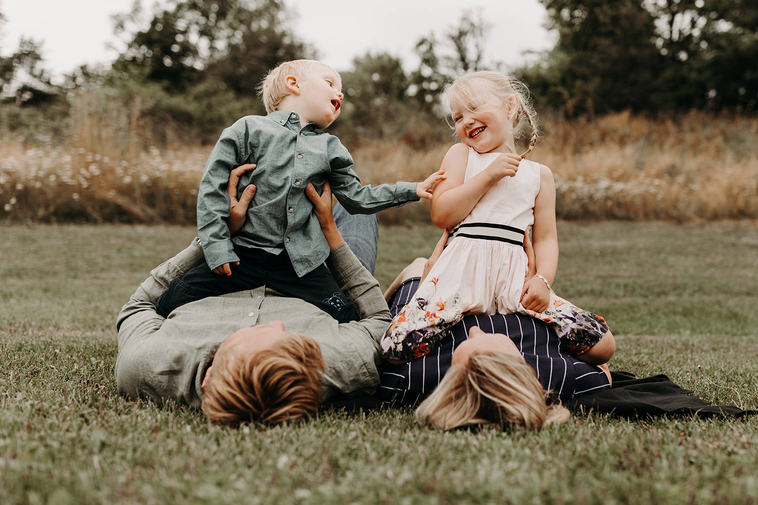Een gezinsfotoshoot buiten legt een gezin vast dat op het gras speelt.
