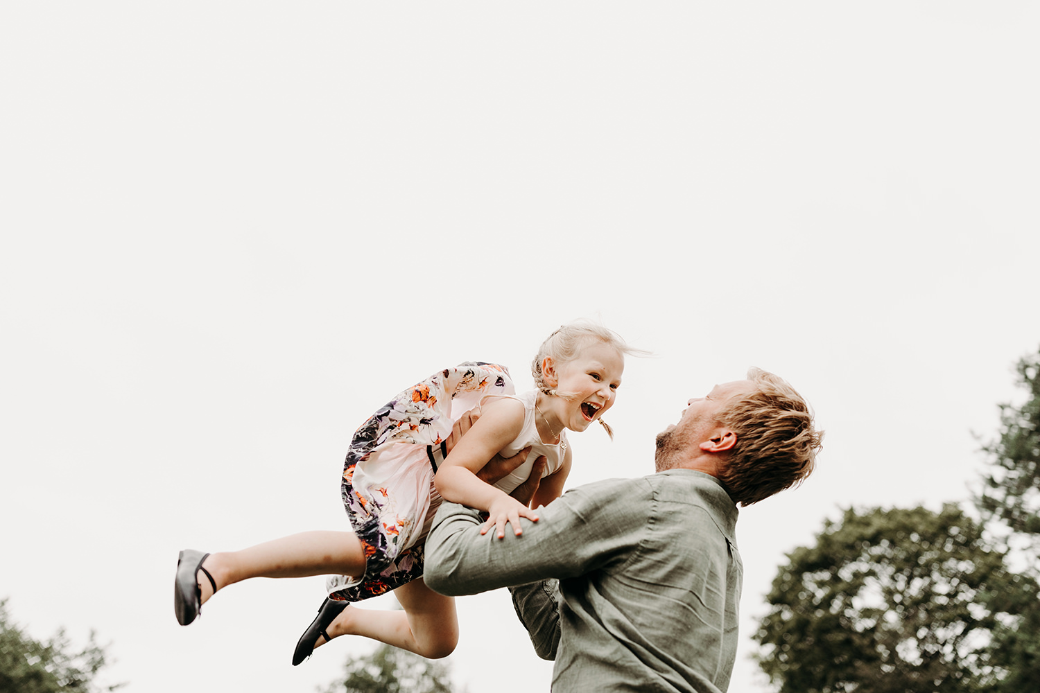 Een man houdt een klein meisje buiten vast tijdens een gezinsfotoshoot.