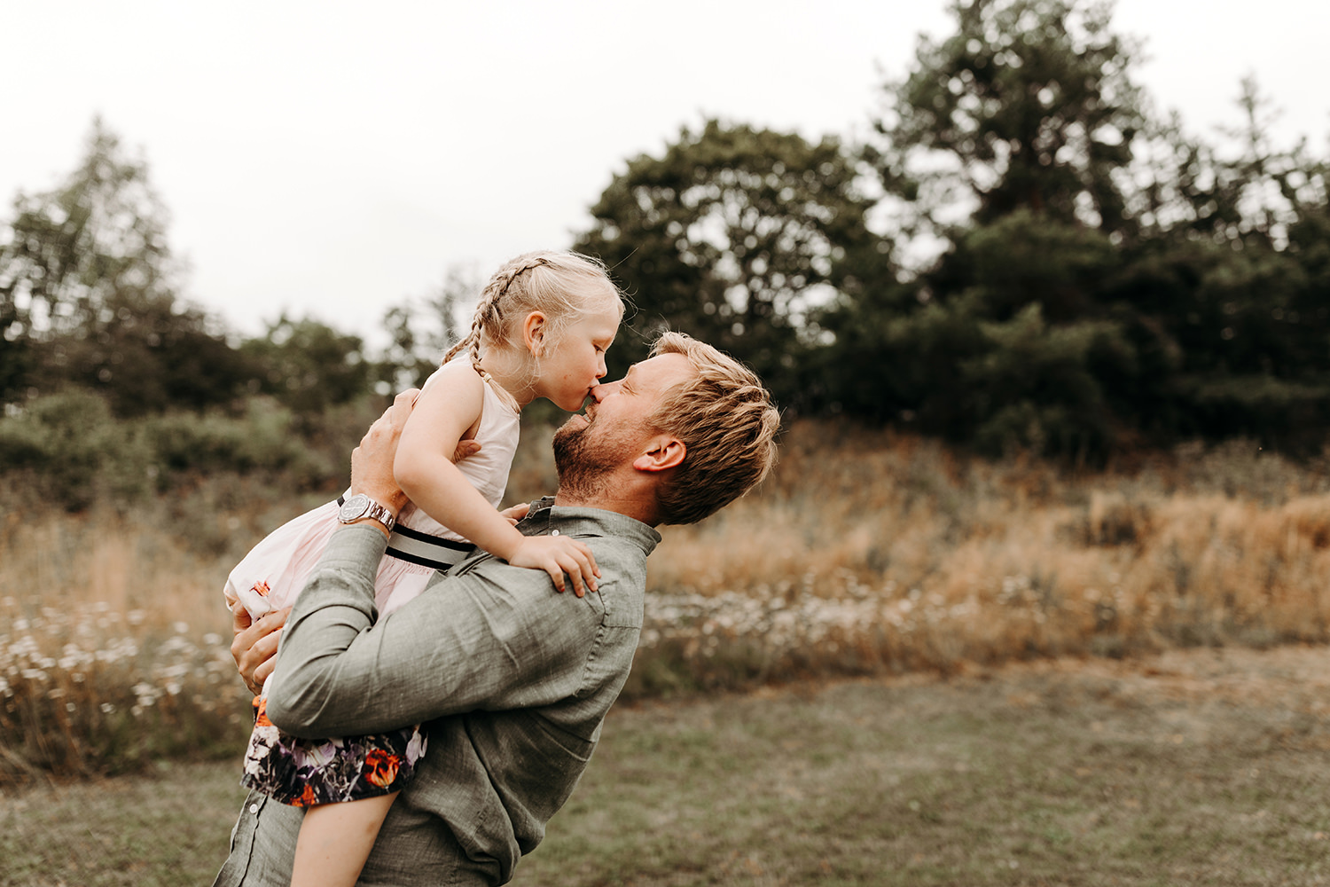 Een man die een klein meisje buiten vasthoudt tijdens een gezinsfotoshoot.