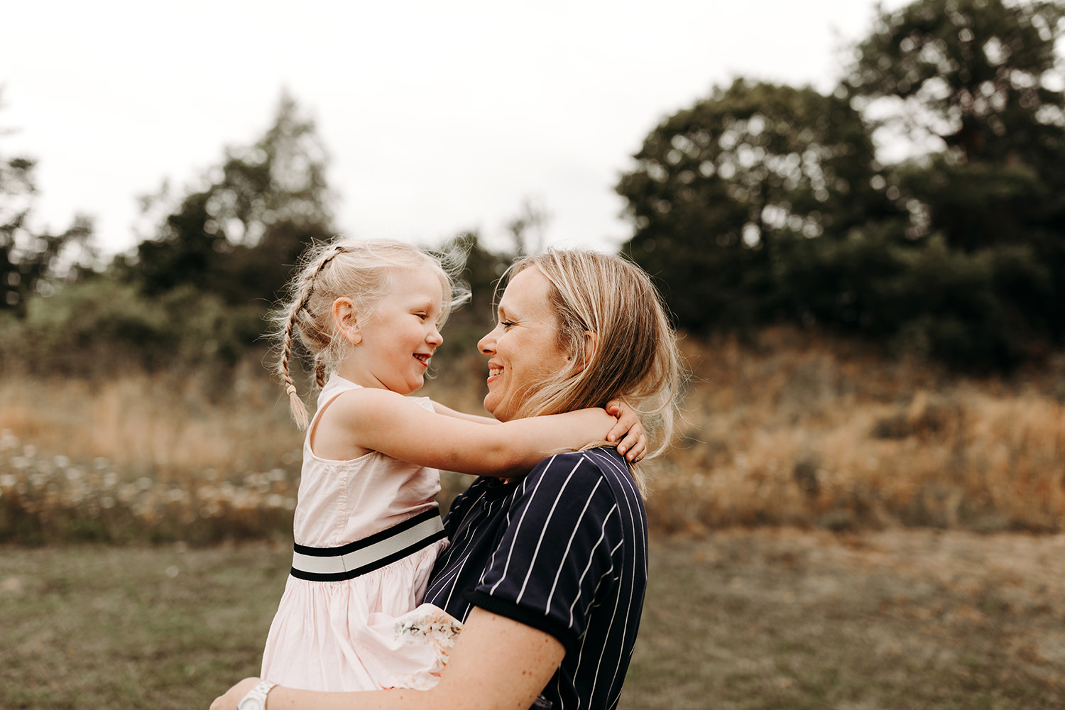 Gezinsfotoshoot buiten met moeder en dochter in een veld.