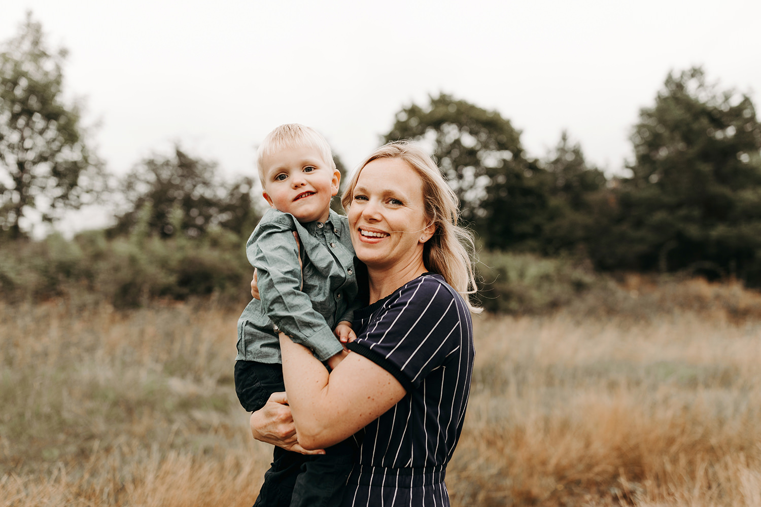 Een vrouw en haar zoon in een veld tijdens een gezinsfotoshoot buiten.