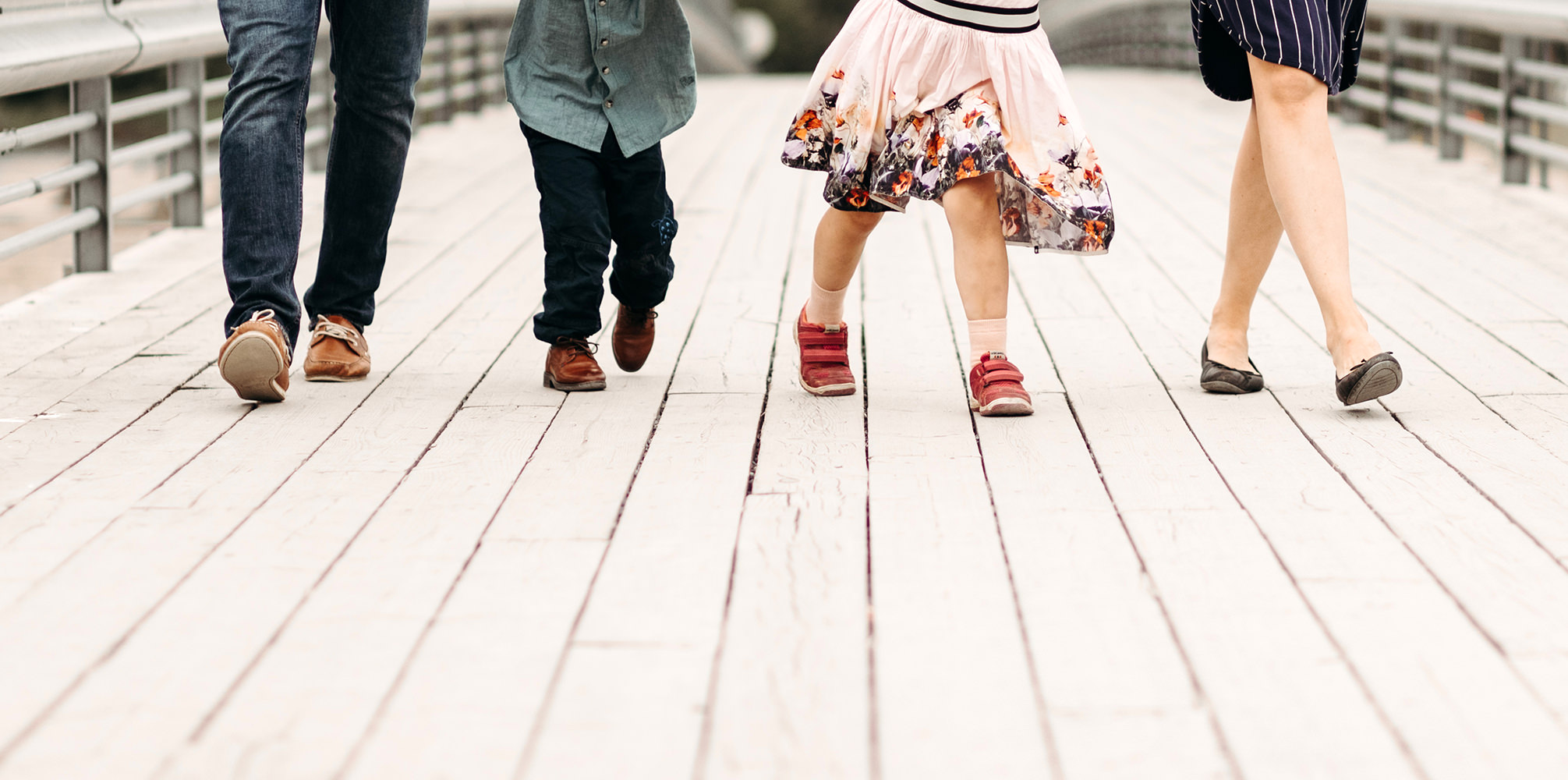 Een gezin geniet van een gezinsfotoshoot buiten op een houten brug.