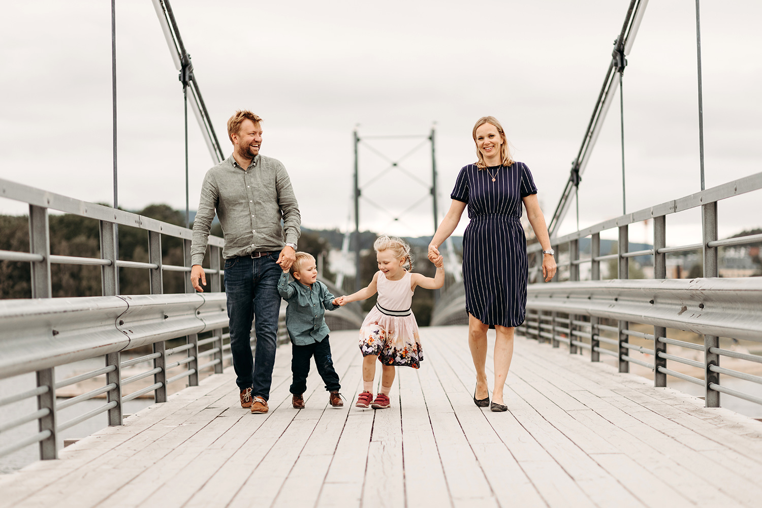 Een gezin loopt over een brug tijdens een gezinsfotoshoot buiten