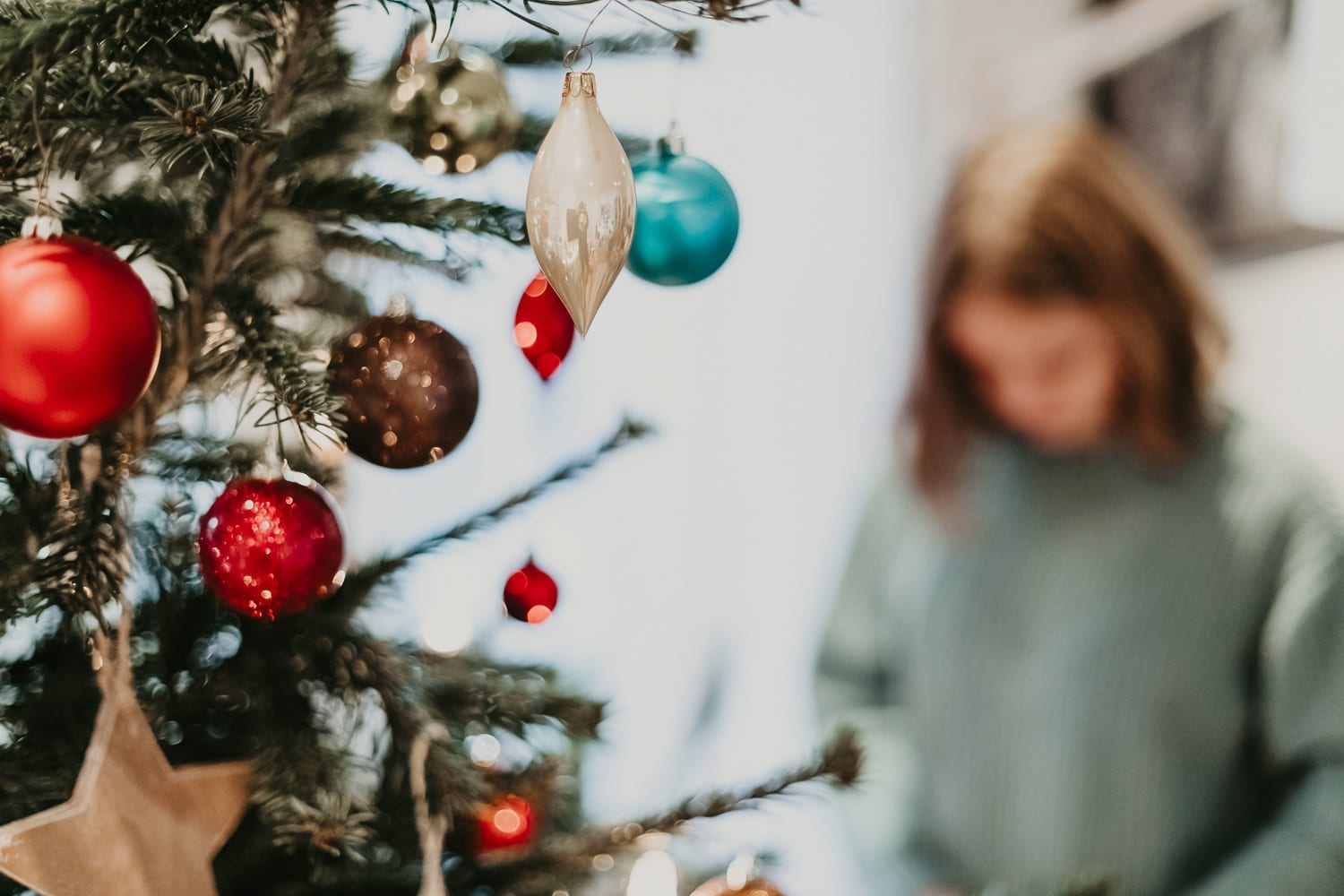 Photo of girl in green pullover decorating the Christmas tree and Christmas decorations