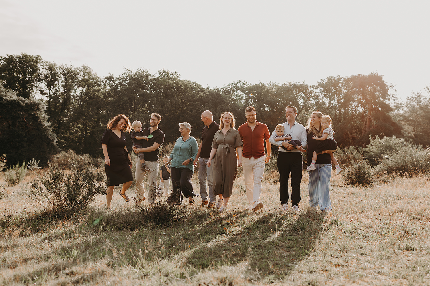 Spontane, leuke foto van een uitgebreide familie tijdens een familiefotoshoot buiten in ochtend licht
