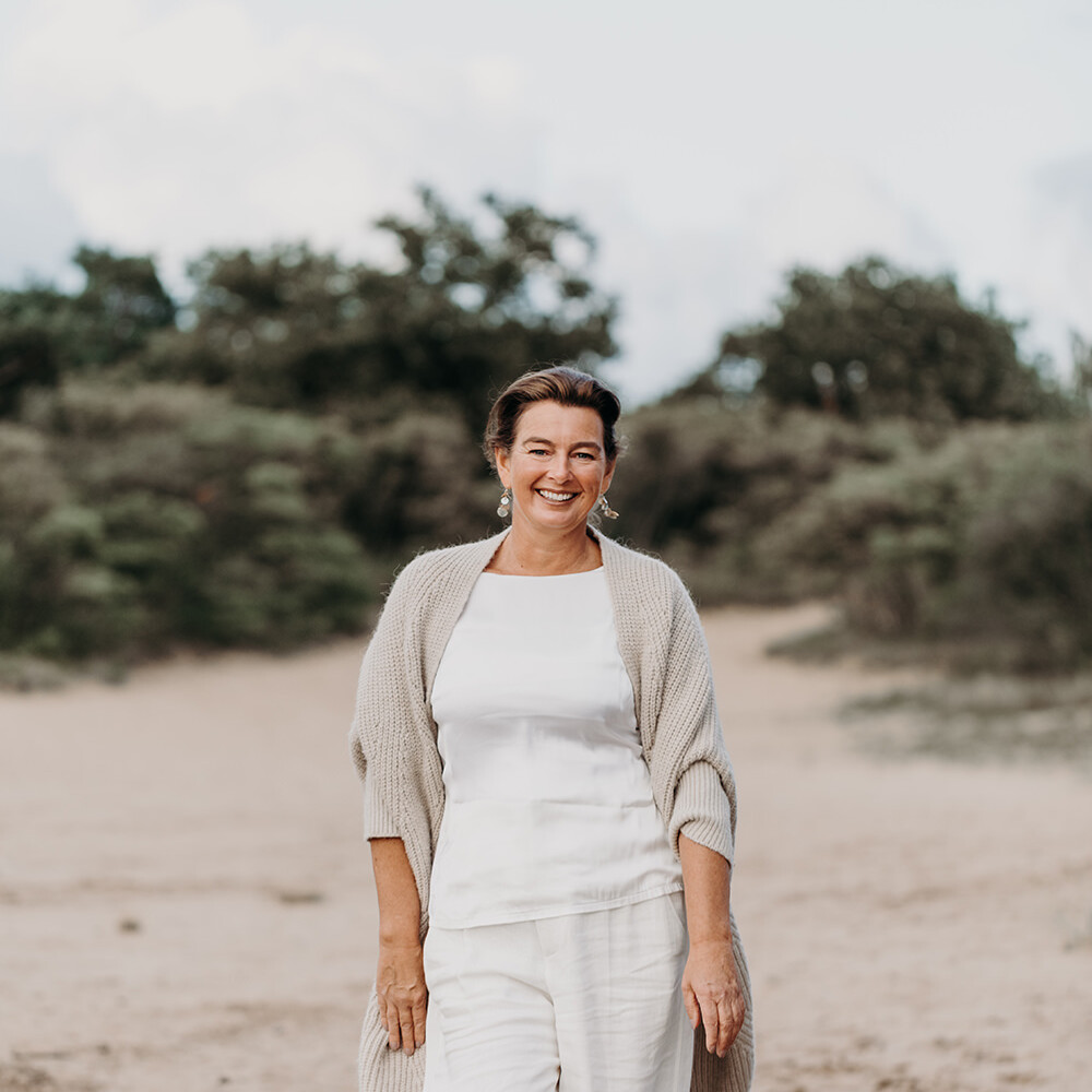 Lifestyle portret van lopend vrouw in witte kleren en vest in de duinen voor personal branding