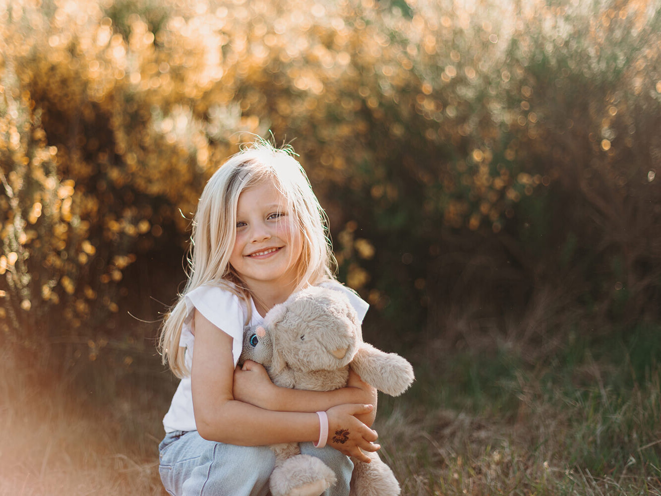 Jong meisje met blond haar en een knuffel tijdens een lente mini fotoshoot met Picturelyspoken in Huizen
