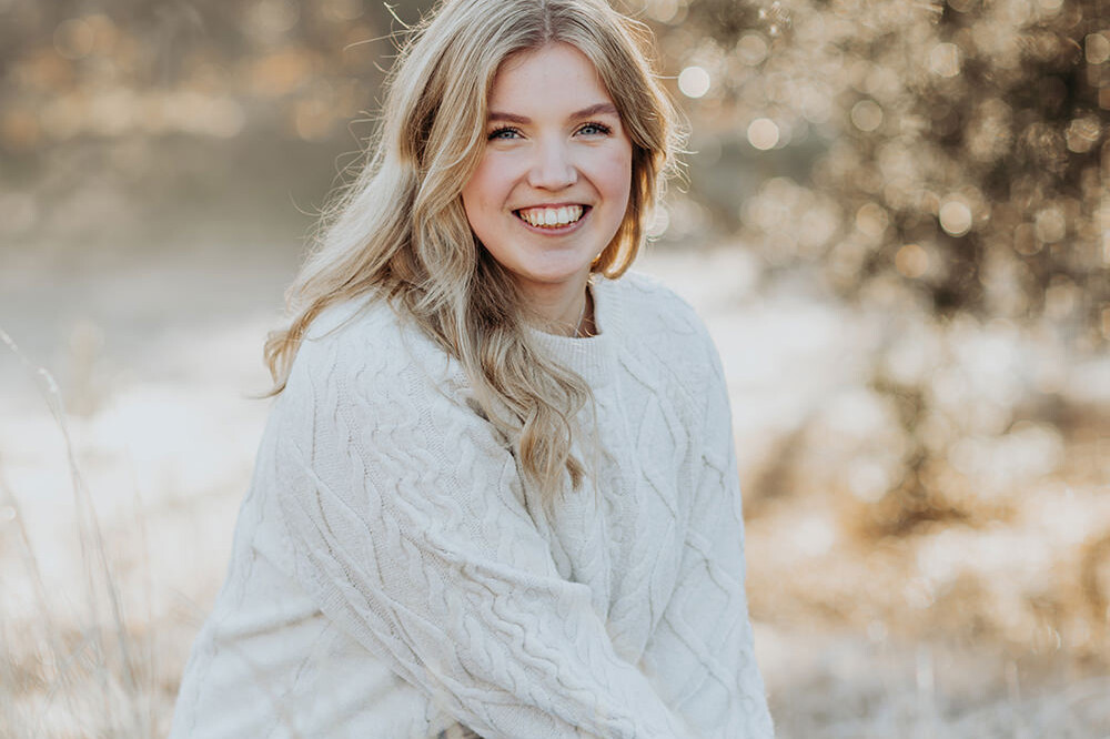 lachende jonge vrouw met lang blond haar tijdens een lifestyle portret fotoshoot en gouden uur licht