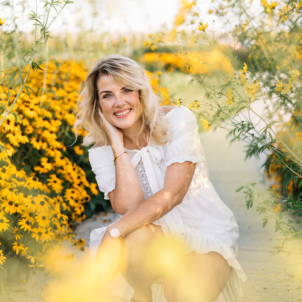Lifestyle portret van vrouw in witte jurk in tussen gele bloemen tijdens een personal branding fotoshoot